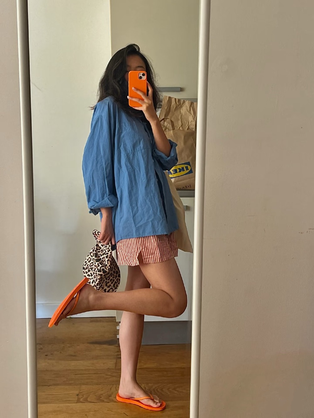 Oversized blue cotton shirt with red striped shorts, orange flip-flops and a leopard print bag