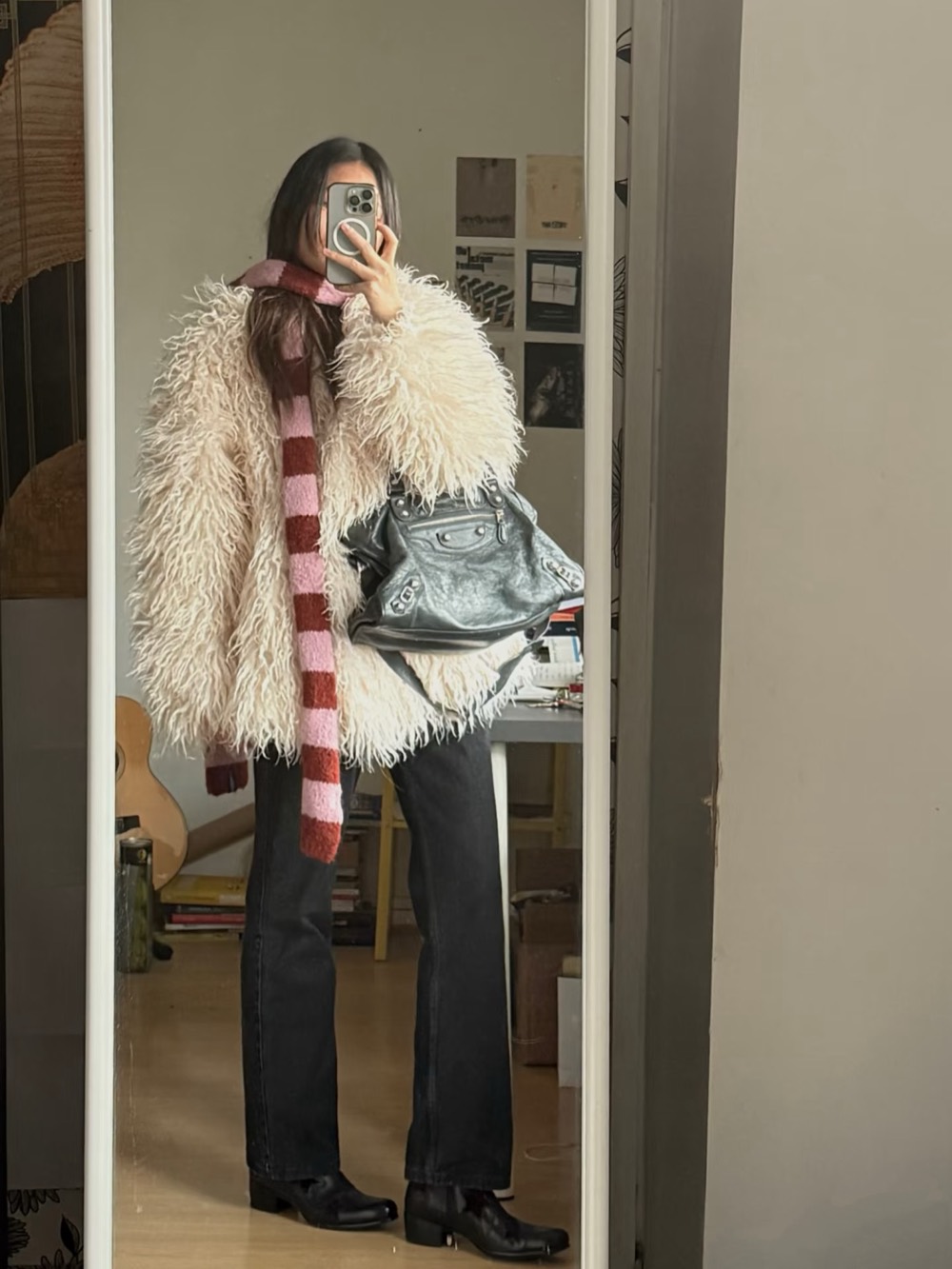 Cream shaggy coat with a pink and red striped scarf, black denim and a grey leather bag